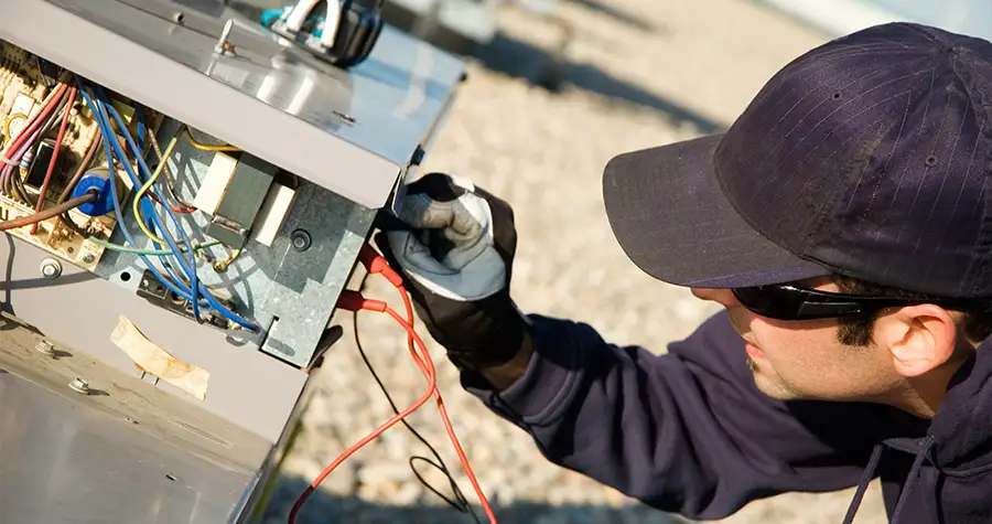 A man checking the wiring inside of an air conditioner