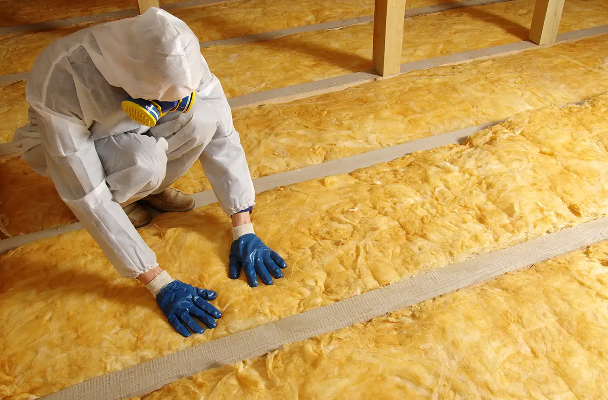 A person installing insulation in an attic